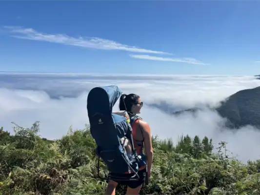 A customer hiking with our baby carrier over a sea of clouds